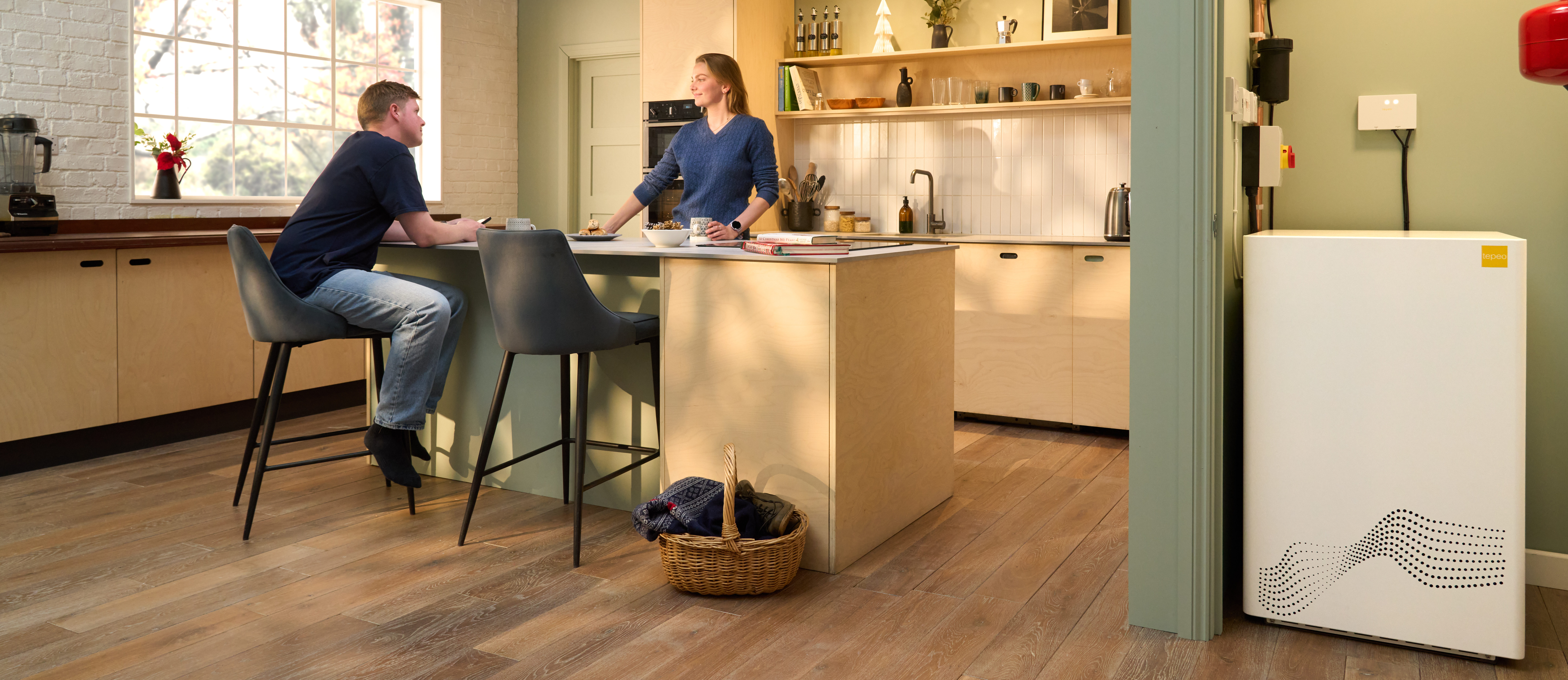 tepeo zeb heat battery boiler in a kitchen while family have coffee