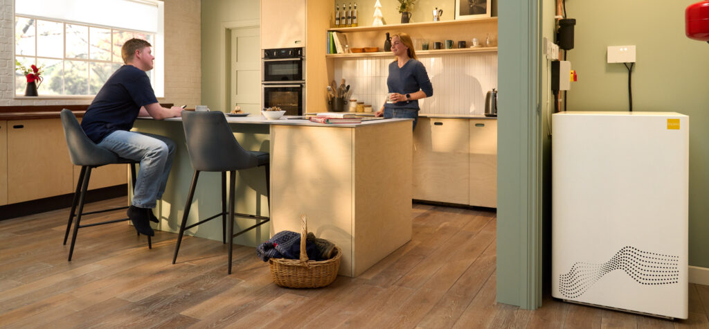 A couple in a modern kitchen with a tepeo ZEB heat battery installed beside the doorway.
